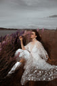 Bride lounging in a lupine wildflower field in silver boots, star lace wedding dress with sheer sleeves, Counting Stars Sample