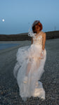 Bride in motion on a gravel lakeshore at dusk, sheer skirt of a star applique wedding dress lifting in the wind, Make a Wish