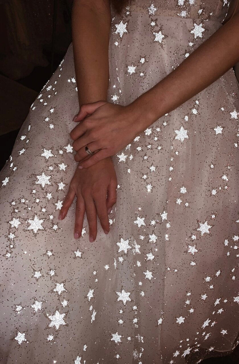 Close-up of a hand resting on a star tulle skirt, reflective stars scattered over the midi wedding dress, celestial, Wild Stars