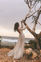 Bride reaching up into a bare tree above the sea, backless ivory lace wedding dress with a full-length skirt, Galaxy Ivory