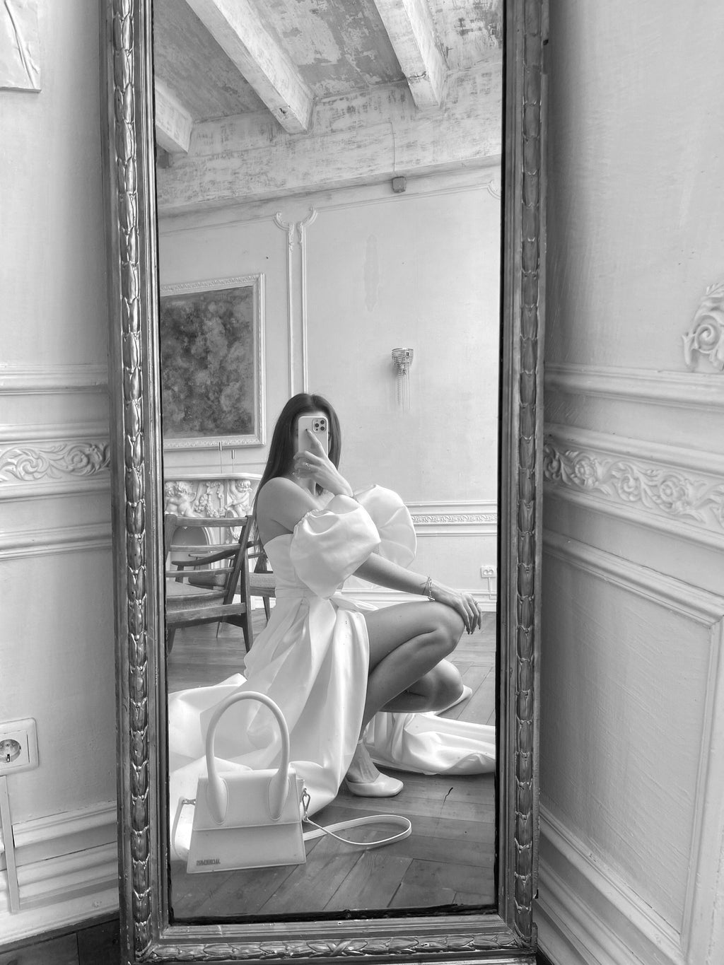 Mirror selfie of a bride crouching in a satin wedding dress with puff sleeves, ornate mirror, black and white, The Dark Side of The Moon