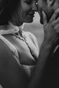 Black and white close-up of a lace wedding dress bodice and necklace as the couple touch foreheads, Chrysanthemum