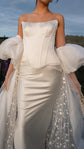 Close crop of an ivory bridal cape with sheer puff sleeves and star tulle train framing a satin corset gown, Aura Cape