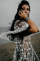 Close-up of sheer ivory star lace sleeves over a black tulle wedding dress, bride touching her face on a cliff, ASH Counting Stars
