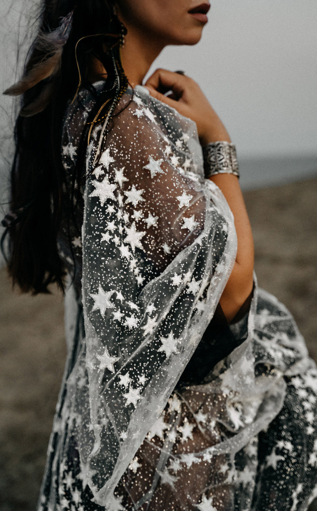 Detail of a sheer star lace sleeve and bodice over black tulle, cropped at the shoulder, ASH Counting Stars wedding dress