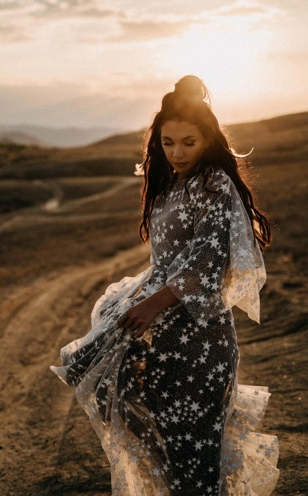 Celestial whimsigoth wedding dress in ivory star lace over black tulle, bride looking down in golden sunset light, ASH Counting Stars
