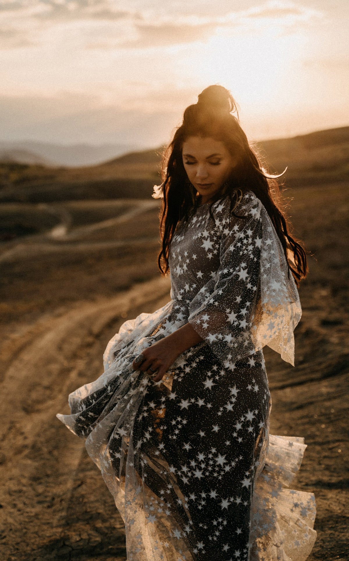 Celestial whimsigoth wedding dress in ivory star lace over black tulle, bride looking down in golden sunset light, ASH Counting Stars