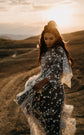 Celestial whimsigoth wedding dress in ivory star lace over black tulle, bride looking down in golden sunset light, ASH Counting Stars