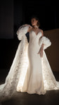 Bridal cape with stars inside the train glowing in a single spotlight, one hand raised to the shoulder, ivory slip gown, Aura Cape