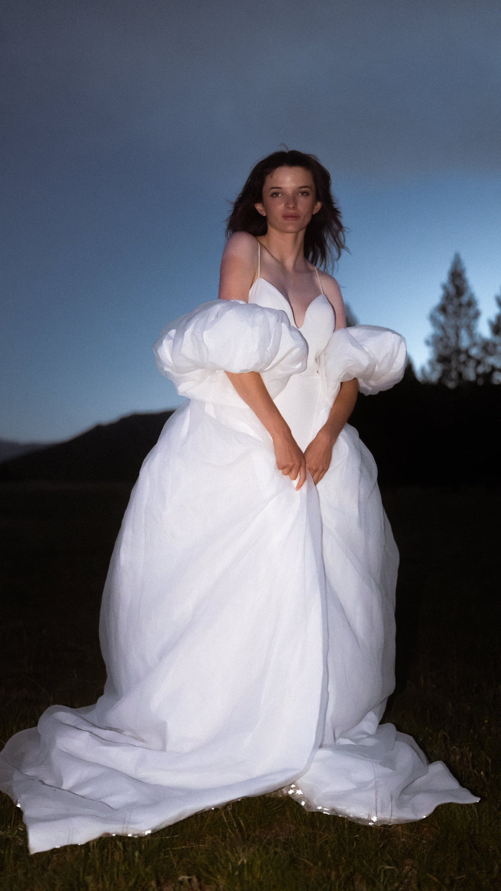 Ivory bridal cape worn closed in front like a full chiffon skirt, puff sleeves at the hips, bride in a field at night, Aura Cape