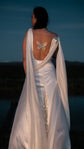Blue hour back view of a satin wedding dress with butterfly embroidery and draped chiffon wings, stars on the train, Aurora
