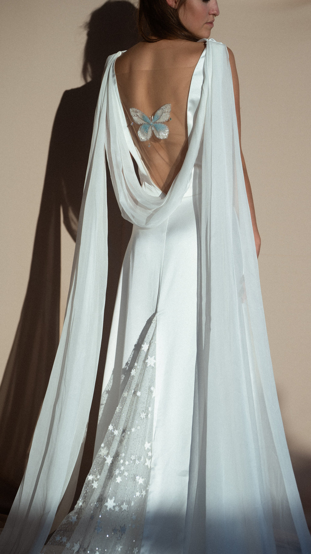 Studio back view of a satin wedding dress with cowl back, blue embroidered butterfly and stars on the train, Aurora