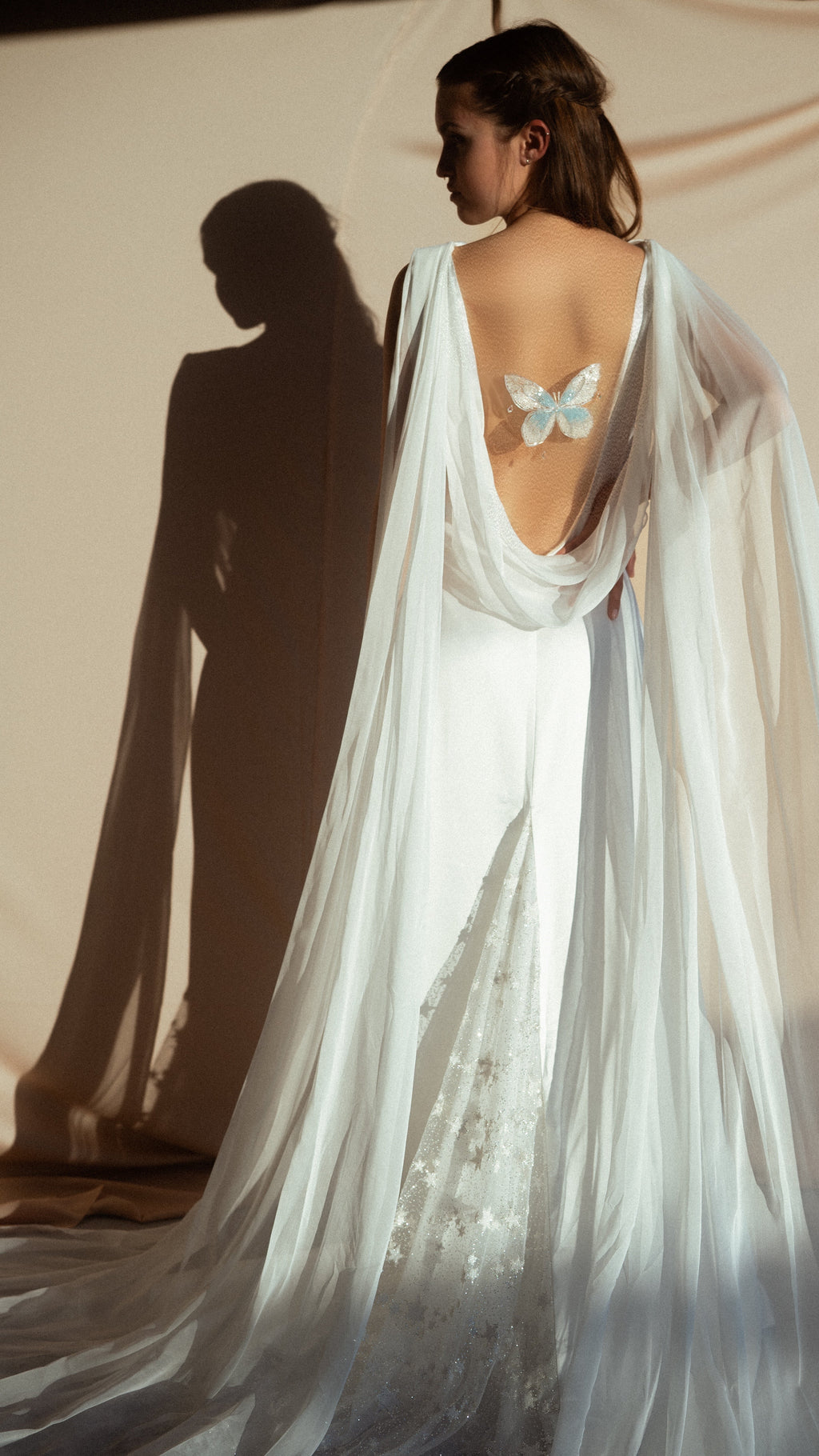 Satin open back wedding dress with draped chiffon wings and embroidered butterfly, star tulle at the train, studio shadows, Aurora