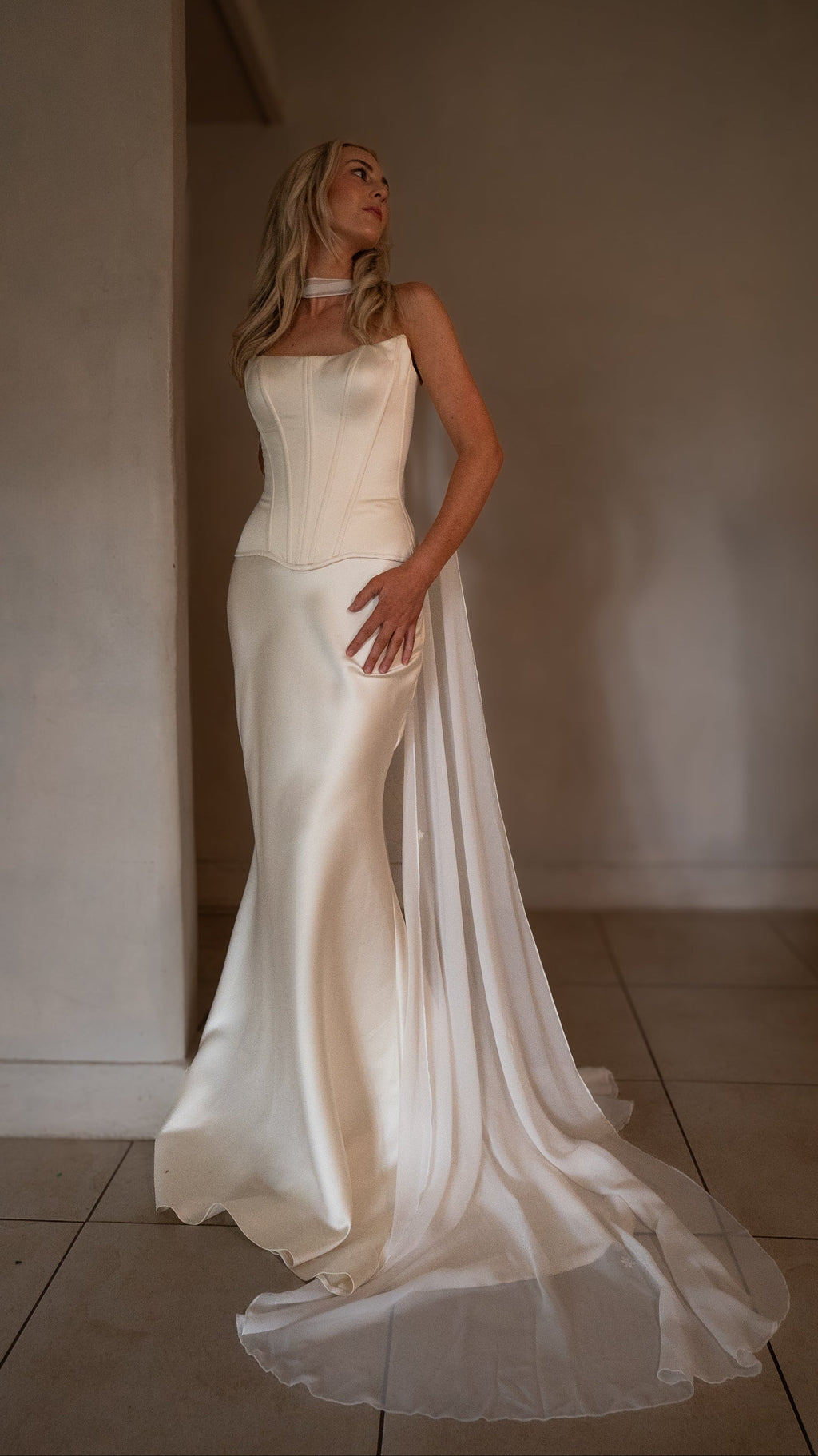 White chiffon bridal scarf knotted at the throat and trailing beside a satin corset gown with a long train, Celeste Scarf