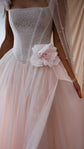 Close-up of a lace corset bodice and silk flower on a blush tulle wedding dress, pearl veil edge at the side, Chrysanthemum