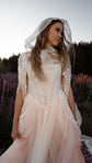 Blush corset wedding dress with a sheer star-embroidered hooded cape, bride among purple lupines, Chrysanthemum