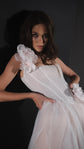 Waist-up view of a lace corset wedding dress bodice with silk flower straps, model leaning in low dramatic light, Chrysanthemum