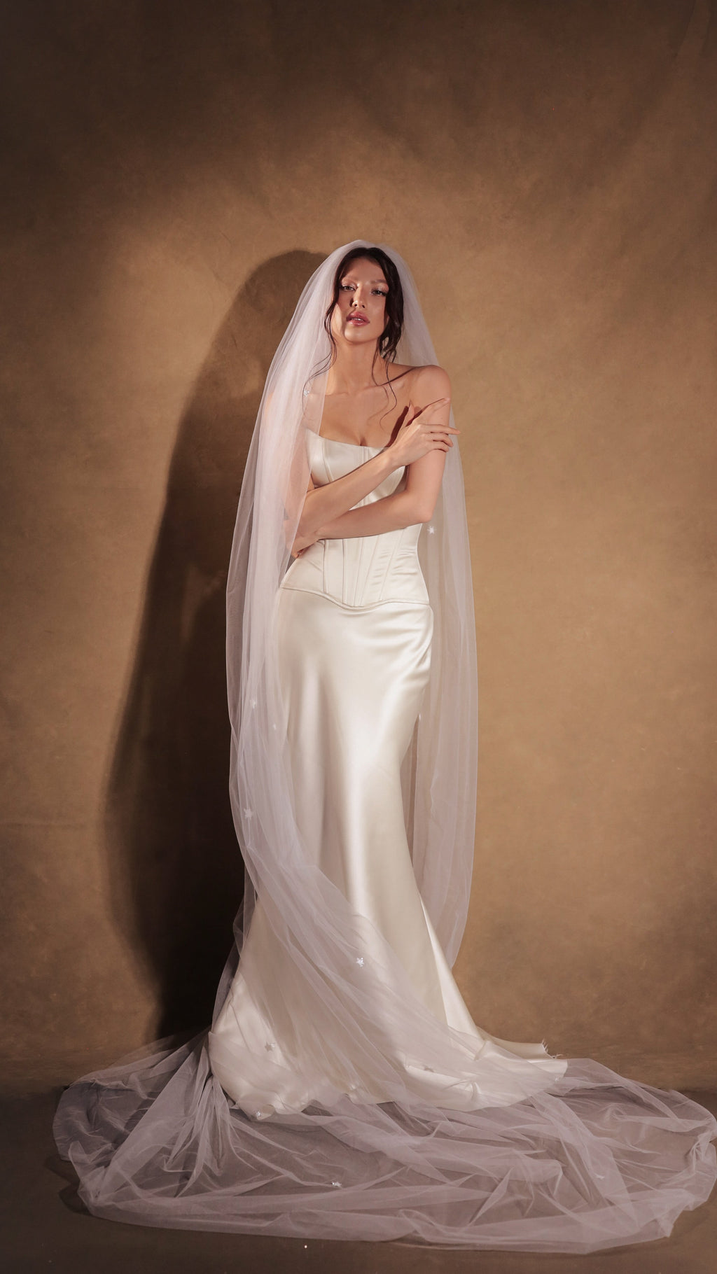 Cathedral celestial wedding veil in soft tulle draped over the head and down to a pooled train, satin corset gown. Coastal Moonlight Veil by Ephemeris