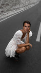 Short wedding dress in star lace with puff sleeves and a full mini skirt, bride crouching on an empty mountain road. Cosmic Dancer by Ephemeris