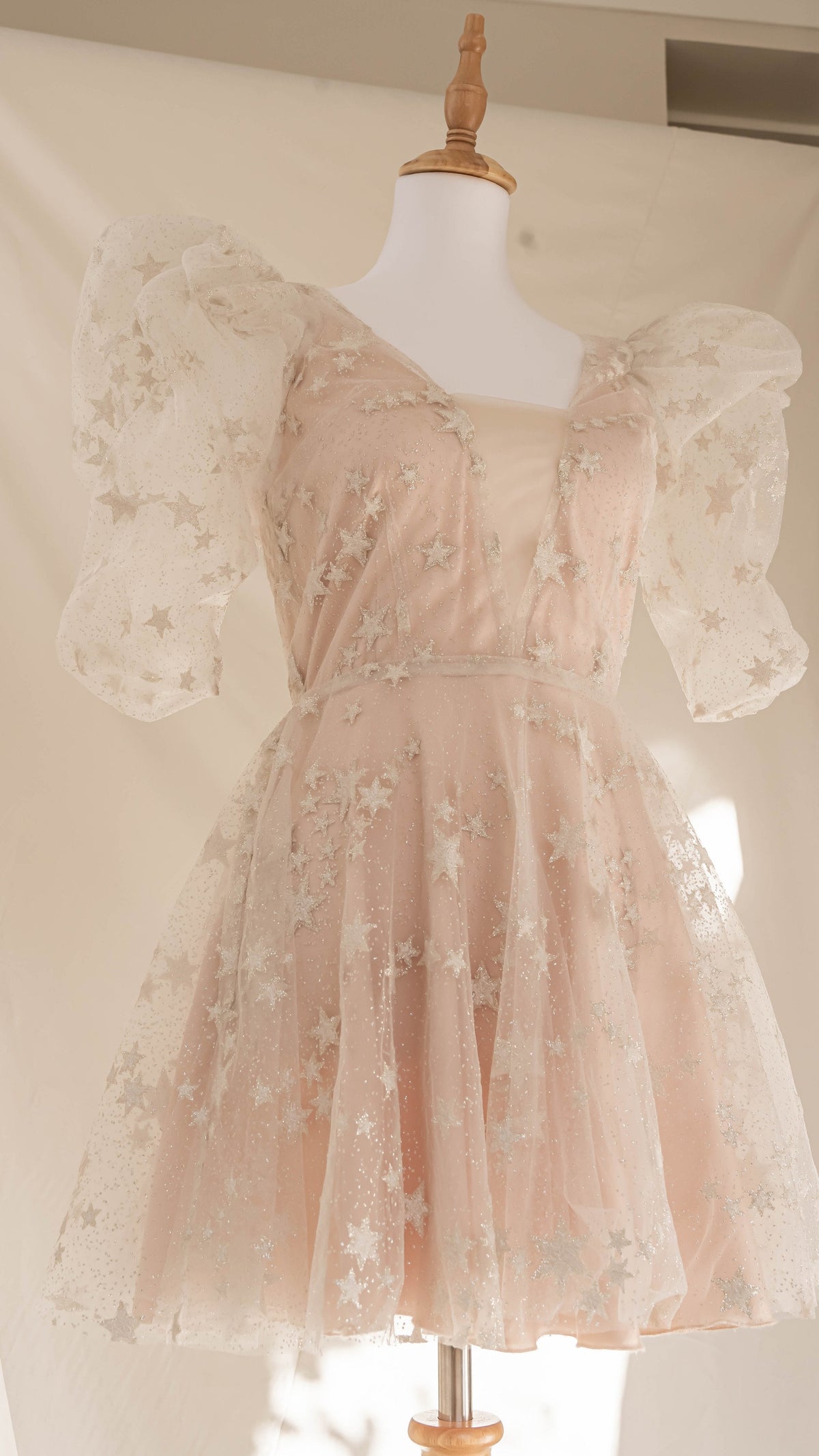 Star lace mini wedding dress with puff sleeves and blush lining on a dress form, full skirt and fitted waist, Cosmic Dancer