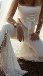 Celestial bridal gloves in soft sheer tulle with hand-placed stars, bride kneeling in a satin corset and flared trousers. Cosmic Gloves by Ephemeris