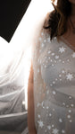 Close-up of reflective star lace over the satin bodice of a wedding dress, backlit tulle veil at the edge, Counting Stars 2.0