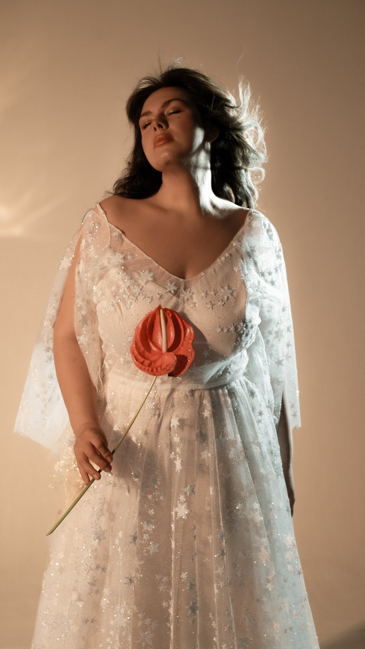 Bride with eyes closed holding a red anthurium, V-neck star lace wedding dress with sheer sleeves, Counting Stars 2.0