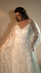 Bride gathering the sheer skirt of a star lace wedding dress, satin slip visible under thin straps, Counting Stars 2.0