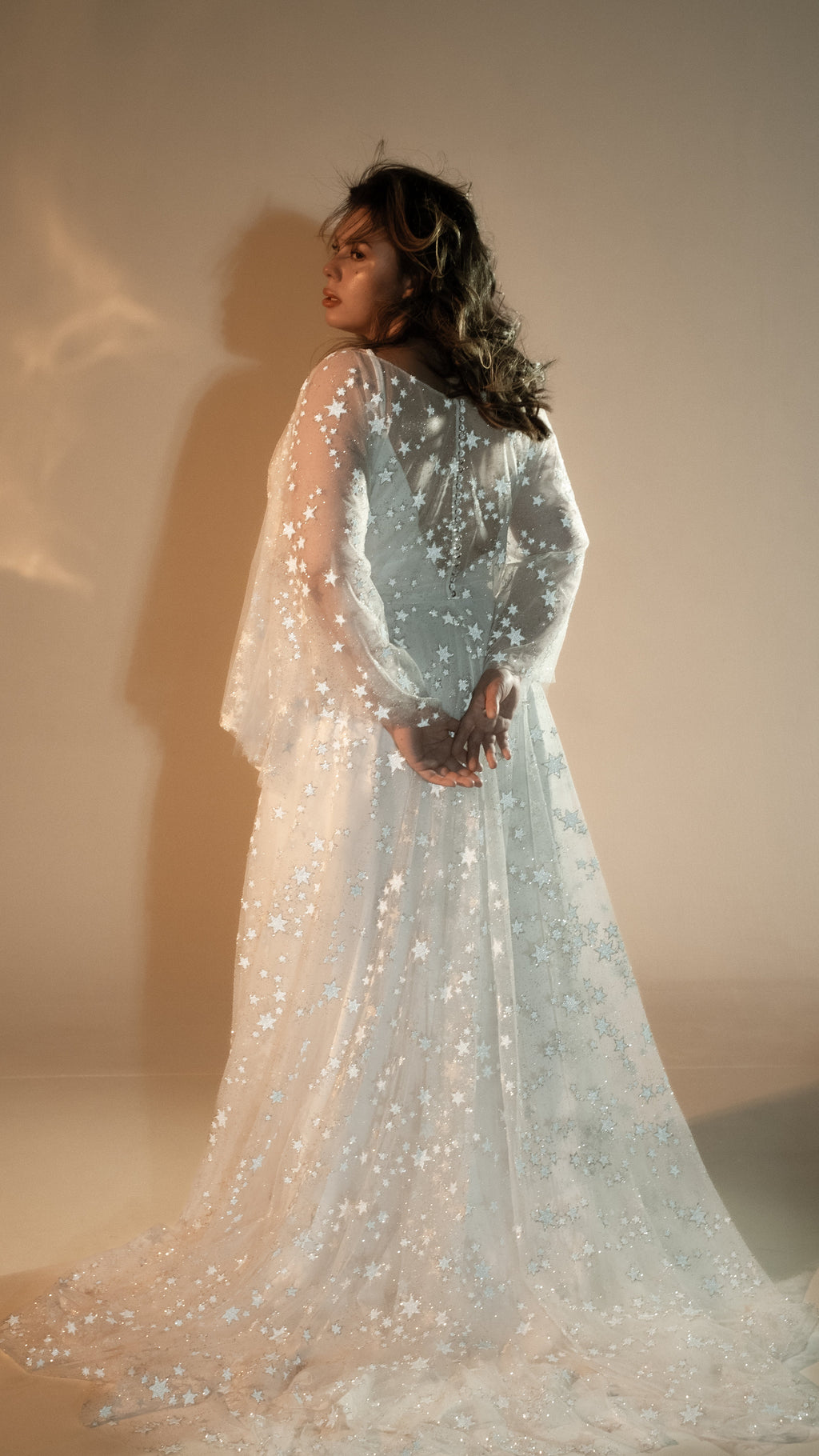 Back view of a bride with hands clasped behind, star lace wedding dress with bell sleeves and long train, Counting Stars 2.0