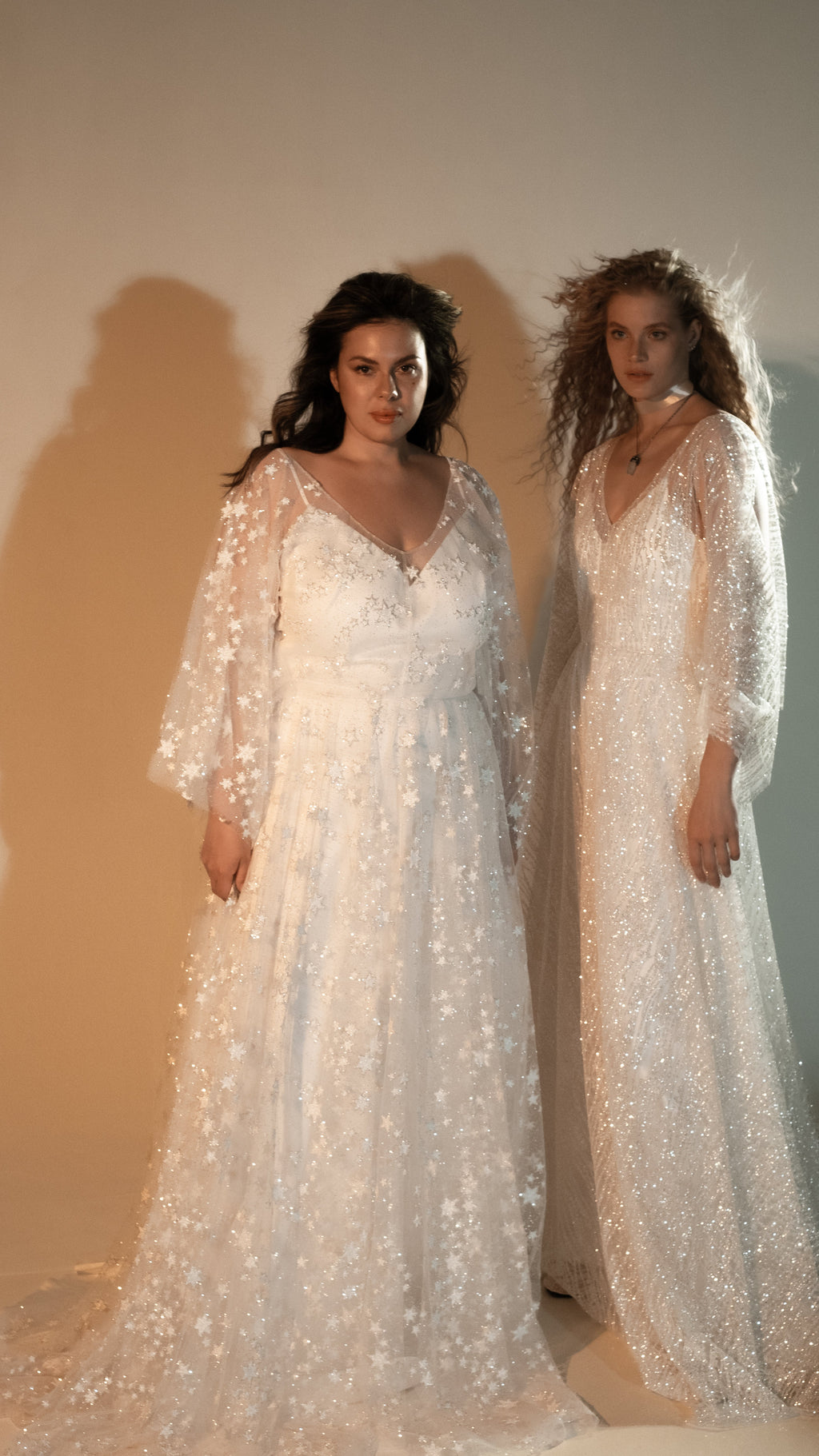 Two models in ivory star lace wedding dresses with long sheer sleeves, front view in warm studio light, Counting Stars 2.0