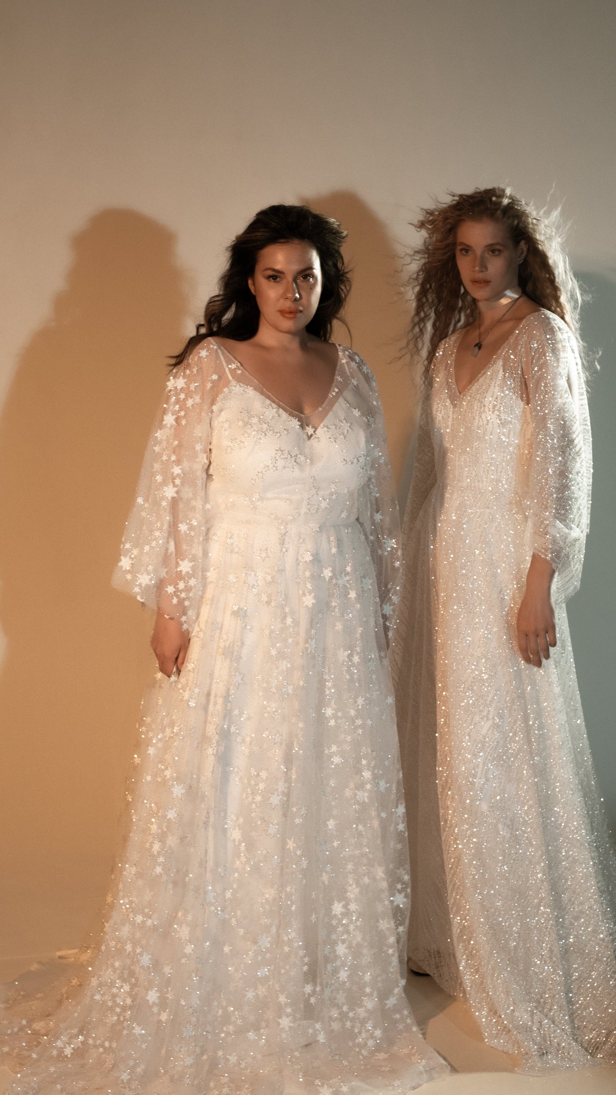 Two models in ivory star lace wedding dresses with long sheer sleeves, front view in warm studio light, Counting Stars 2.0