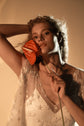 Close crop of a model with a red anthurium at her cheek, star lace wedding dress V-neck and slip, Counting Stars 2.0
