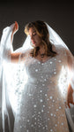 Bride raising a backlit tulle veil above her head, reflective stars glinting on a lace wedding dress, Counting Stars 2.0