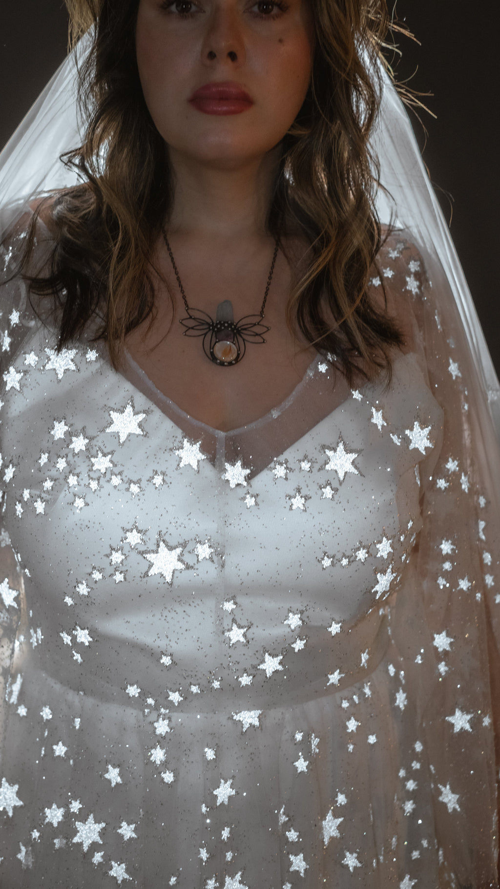Tight crop of the satin V-neck bodice under star lace on a wedding dress, veil and pendant, Counting Stars 2.0