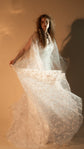 Bride swinging the sheer star lace skirt of her wedding dress out to the side, warm light on a beige wall, Counting Stars 2.0