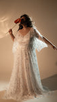 Bride holding a red anthurium to her face, star lace wedding dress with open cape sleeves and a soft train, Counting Stars 2.0