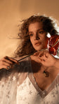 Close portrait with a red flower, V-neck of a star lace wedding dress over a satin slip, pendant necklace, Counting Stars 2.0