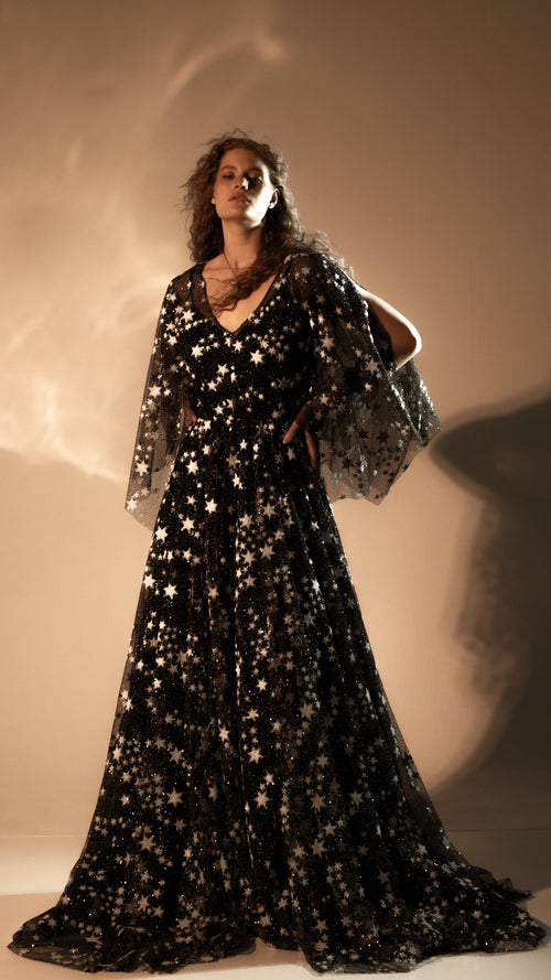 Black celestial wedding dress with silver star lace and sheer cape sleeves, full-length front view. Counting Stars Black by Ephemeris