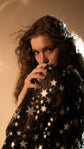 Bride holding the sheer star lace sleeve of her black wedding dress to her face, Counting Stars Black