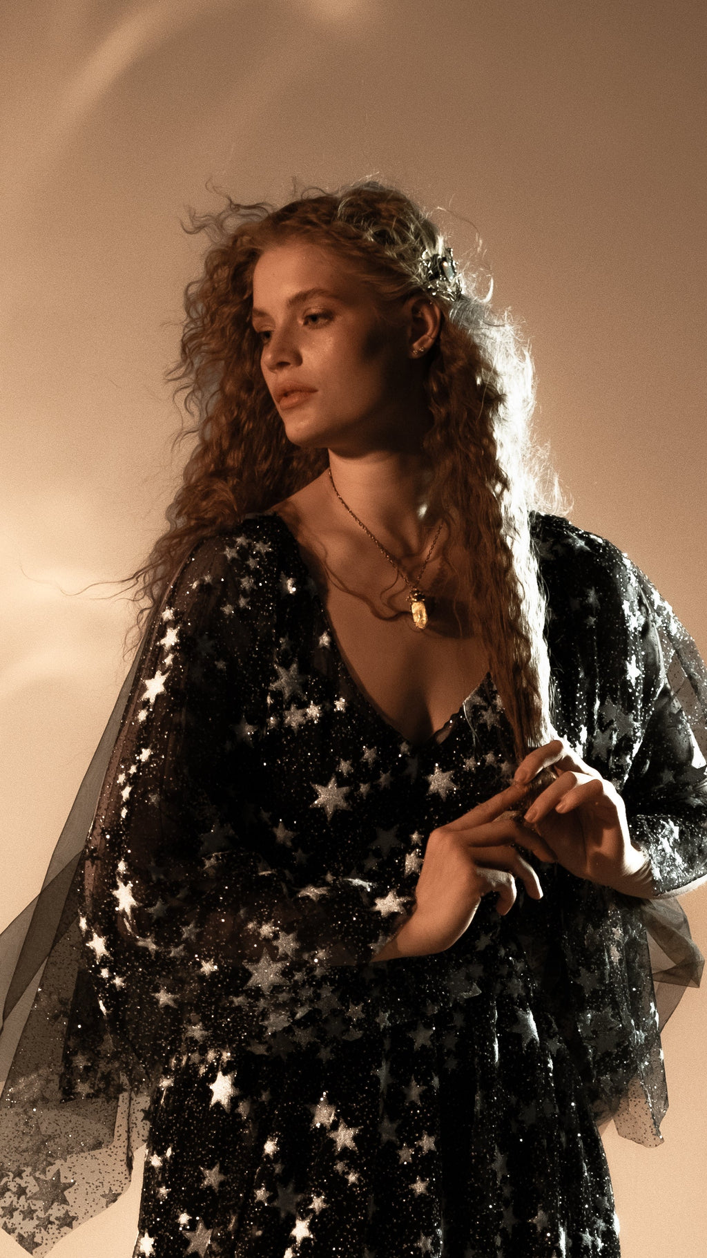 Bride in profile wearing a black starry wedding dress with sheer star lace sleeves, warm studio light, Counting Stars Black