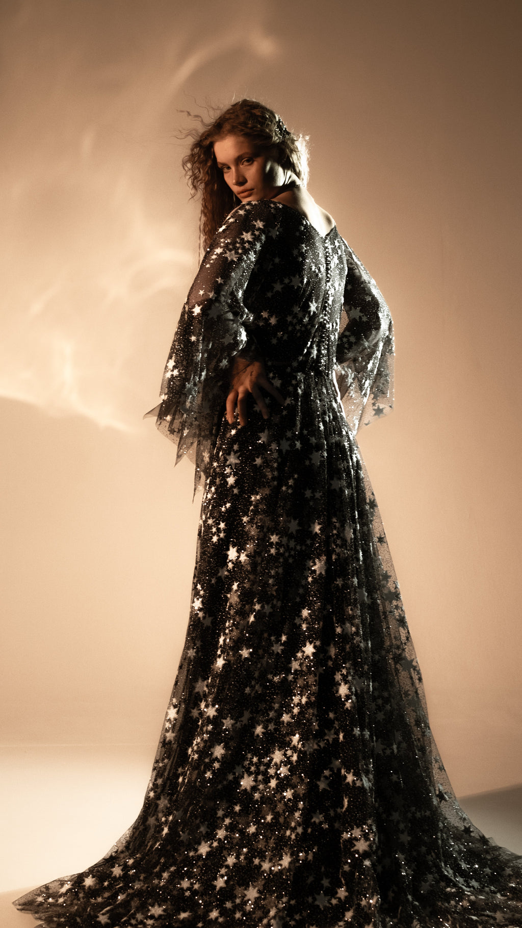 Back view of a black celestial wedding gown with star lace train and sheer cape sleeves, Counting Stars Black