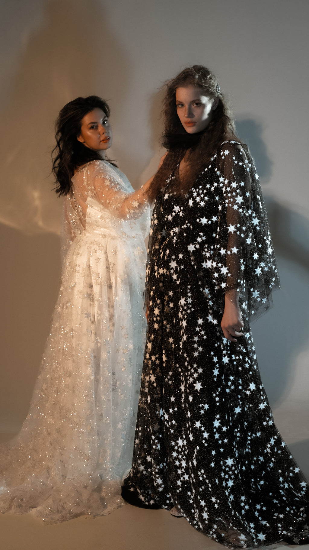 Two brides side by side in black and ivory star lace wedding dresses from the Counting Stars collection, Counting Stars Black
