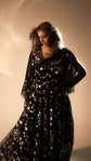 Bride with head bowed in a black star lace wedding dress with fluttering sheer sleeves, Counting Stars Black