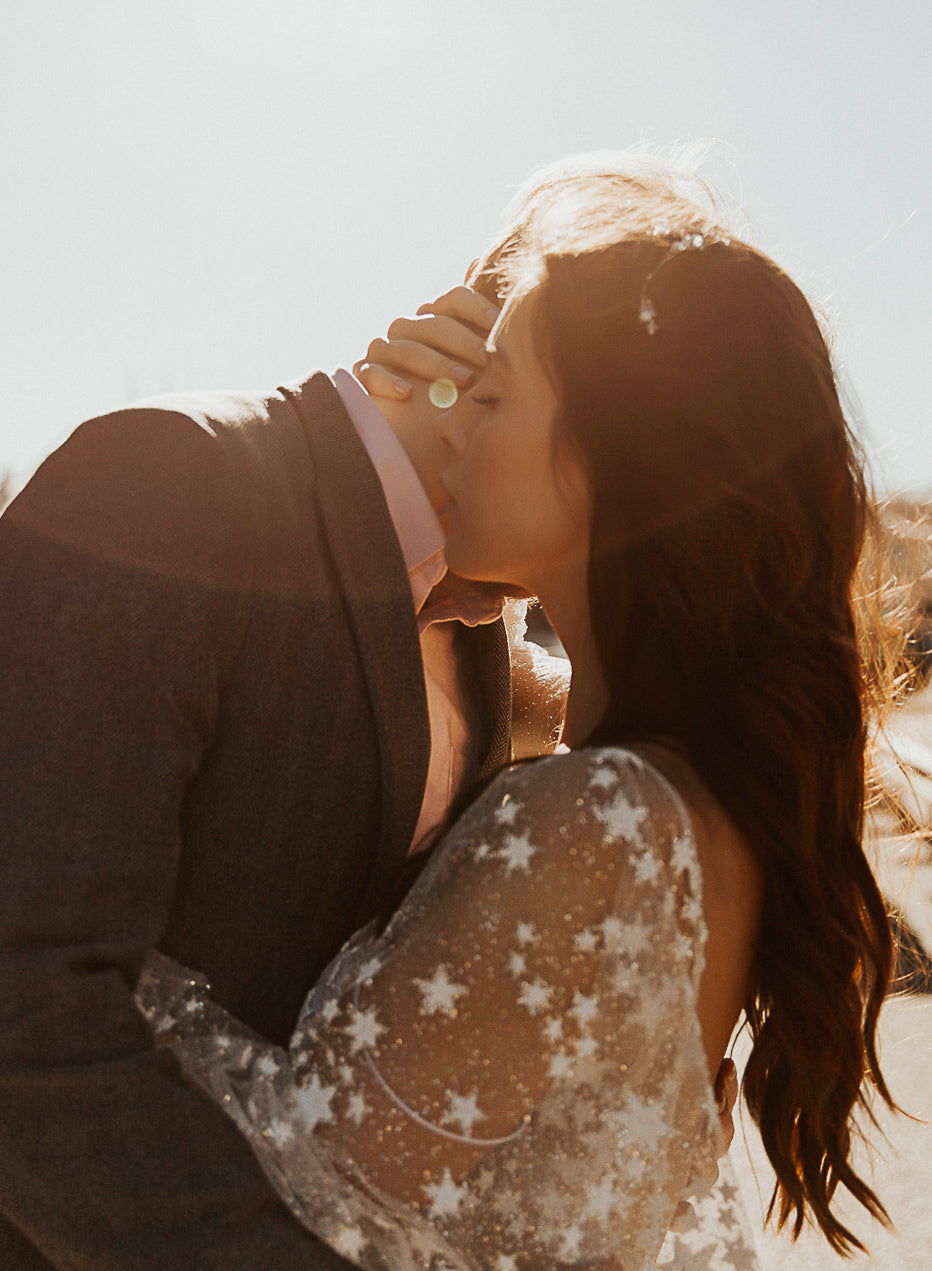 Close-up of a couple kissing in golden light, star lace sleeve of a sheer wedding dress, Counting Stars Sample