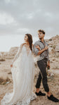 Bride beside the groom in the desert, spreading the sleeve of a deep V star lace wedding dress, Counting Stars Sample