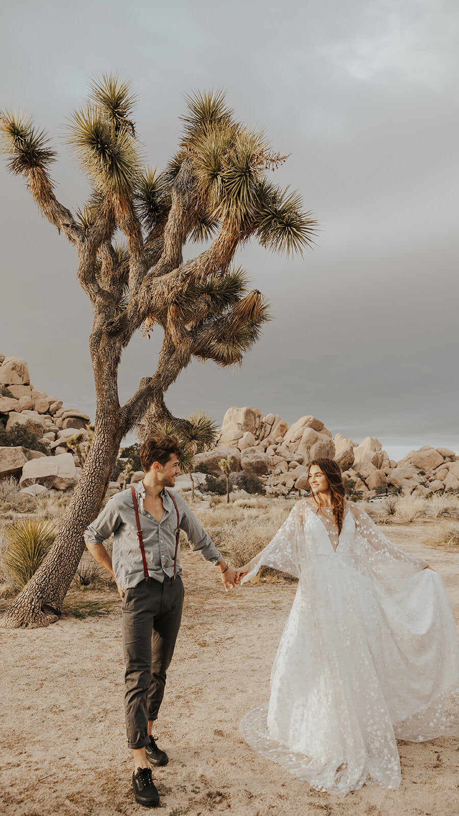 Couple holding hands by a Joshua tree, bride swinging the sleeve of a star lace wedding dress, Counting Stars Sample