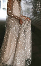 Close crop of a hand lifting the sheer star lace skirt of a wedding dress in a dim tunnel, Counting Stars Sample