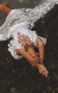 Bride lying on mossy rocks, sheer star lace wedding dress sleeves spread around her, overhead shot, Counting Stars