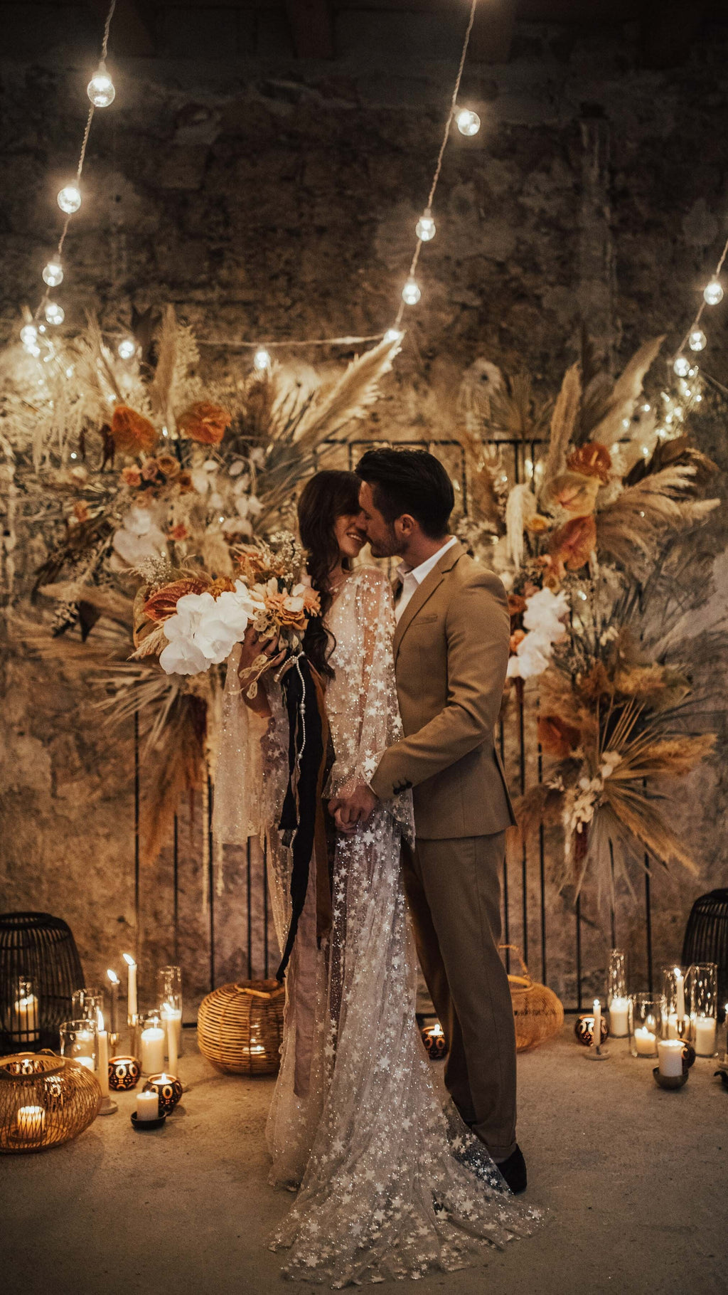 Groom kissing the bride in a long star lace wedding dress, candlelit dried flower ceremony backdrop, Counting Stars