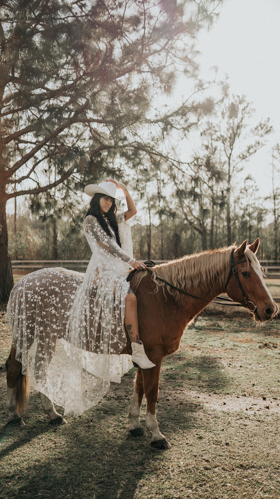 Bride riding a chestnut horse in a cowboy hat, star lace wedding dress draped over the saddle, Counting Stars